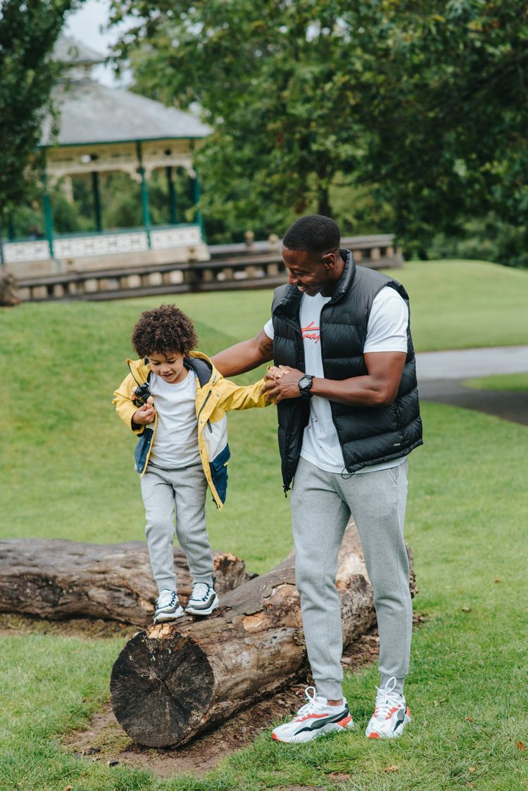 Father helping his son walk across a log by giving him support