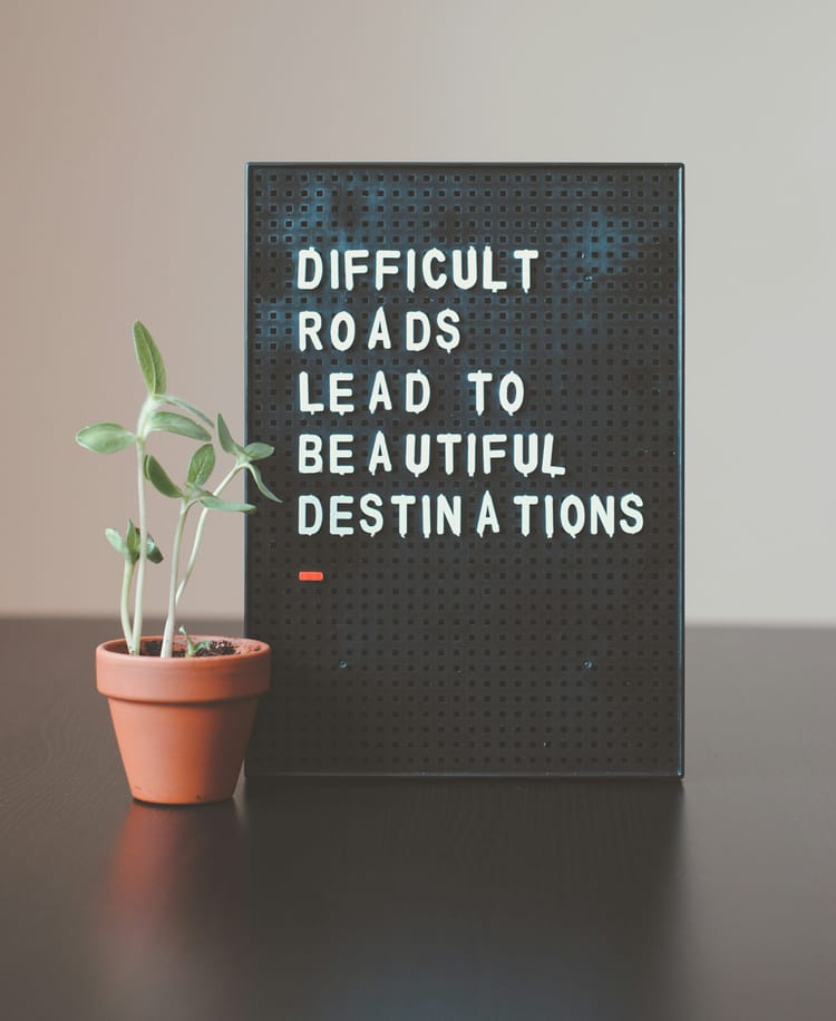 Image of a blackboard with white writing saying, "Difficult roads lead to beautiful destinations."